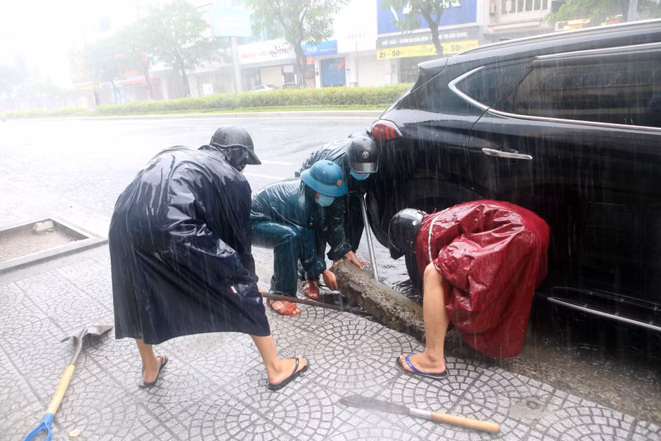 Dân quân phường Nam Dương (quận Hải Châu) tiến hành thông cửa thu nước trên các tuyến đường để chống ngập. (Ảnh: Trần Lê Lâm/TTXVN)