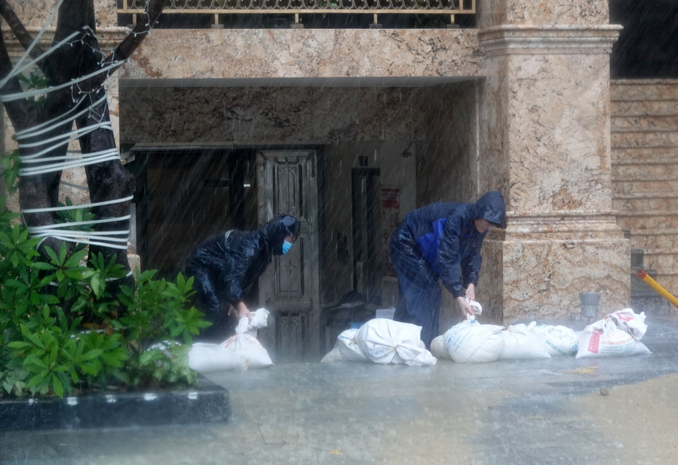 Chủ một khách sạn trên đường ven biển Võ Nguyên Giáp khẩn trương dùng bao cát để chặn nước lối vào hầm. (Ảnh: Quốc Dũng/TTXVN)