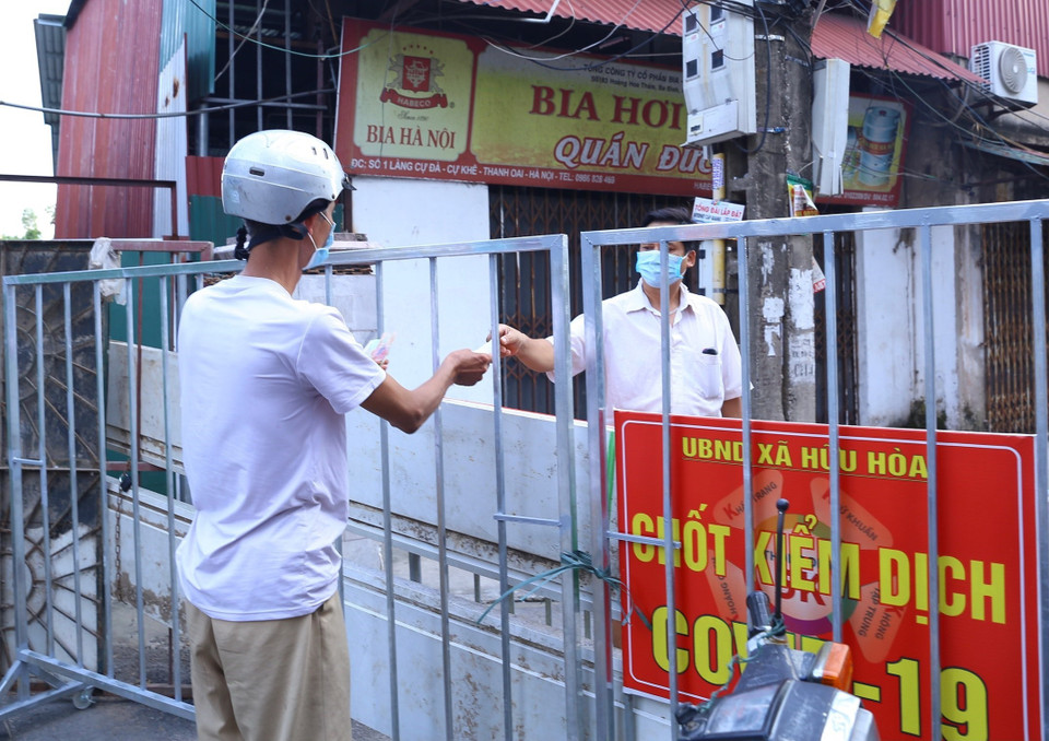 Người dân xã Hữu Hòa (Thanh Trì) giao dịch qua rào chắn.(Ảnh: Hoàng Hiếu/TTXVN)