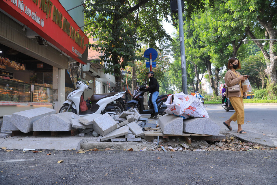 Vật liệu xây dựng để tràn lan trên vỉa hè khiến người dân phải đi bộ dưới lòng đường gây mất an toàn giao thông. (Ảnh: Hoàng Hiếu/TTXVN)