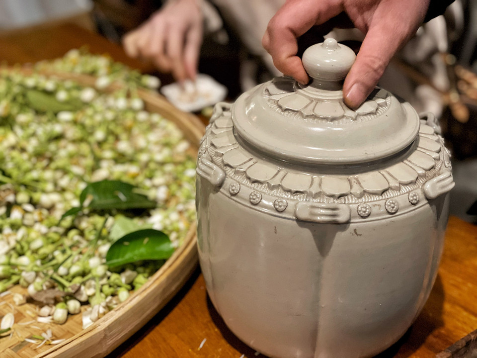 Để ướp trà có thể dùng hộp giấy các-tông, nồi hoặc thạp gốm sứ... Tuy nhiên, cần đặc biệt lưu ý công đoạn đảo trà (thông hoa), cho trà bay bớt hơi ẩm. Quá trình đảo trà thực hiện khoảng 2 tiếng mỗi lần trong cả thời gian ướp trà khoảng 2 ngày. (Ảnh: Xuân Mai/Vietnam+)