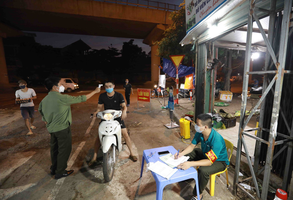 Ban quản lý chợ đầu mối Minh Khai triển khai đo thân nhiệt, khai báo y tế cho tất cả tiểu thương và người dân khi vào trong chợ. (Ảnh: Vũ Sinh/TTXVN)