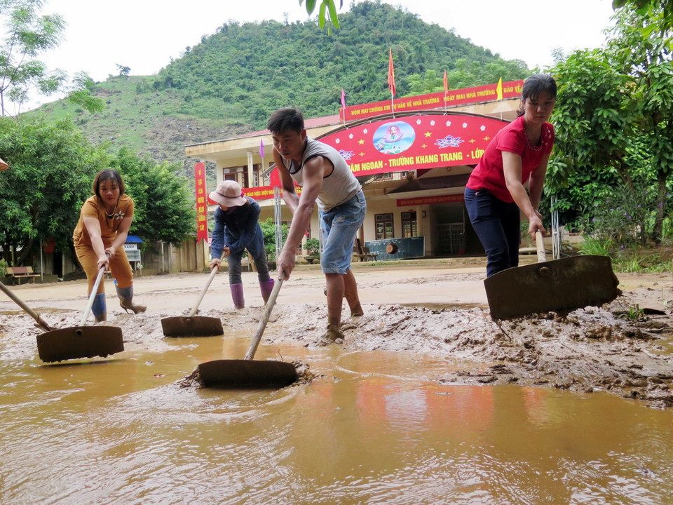 Giáo viên, phụ huynh trường Tiểu học Tân Lang, huyện Phù Yên dọn dẹp bùn đất trên sân trường. (Ảnh: Hữu Quyết/TTXVN)