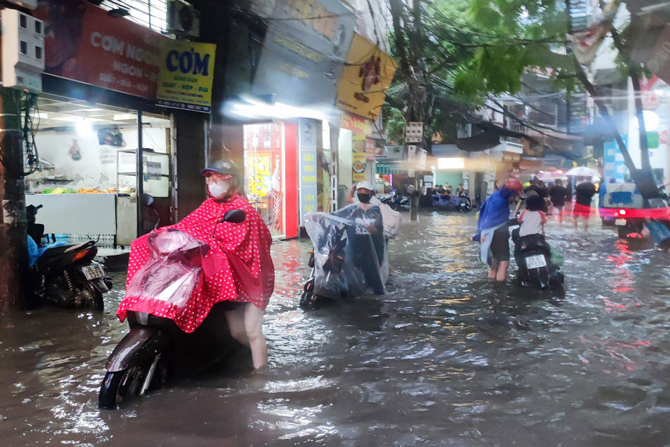 Người dân Thủ đô dắt xe qua khu vực nước ngập sâu. (Ảnh: Hoài Nam/Vietnam+)
