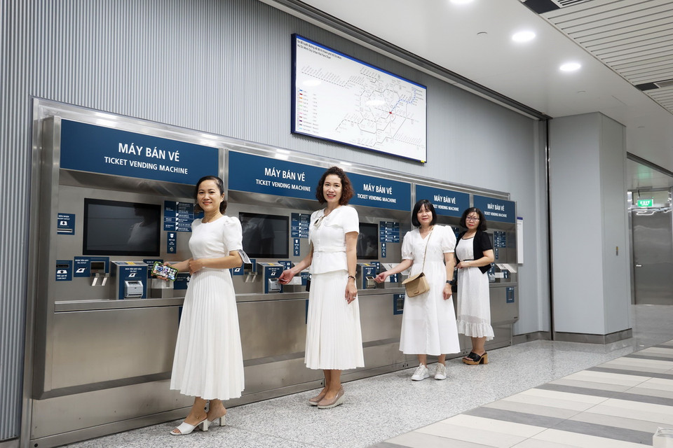 Người dân check-in với máy bán vé metro trước khi trải nghiệm metro vận hành thử đợt cuối cùng. (Ảnh: Huyền Trinh/TTXVN)