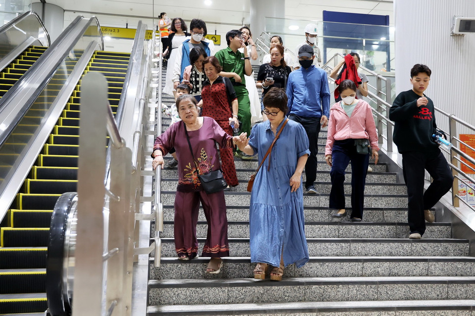 Người lớn tuổi được con cháu hỗ trợ đi trải nghiệm metro số 1. (Ảnh: Hồng Đạt/TTXVN)
