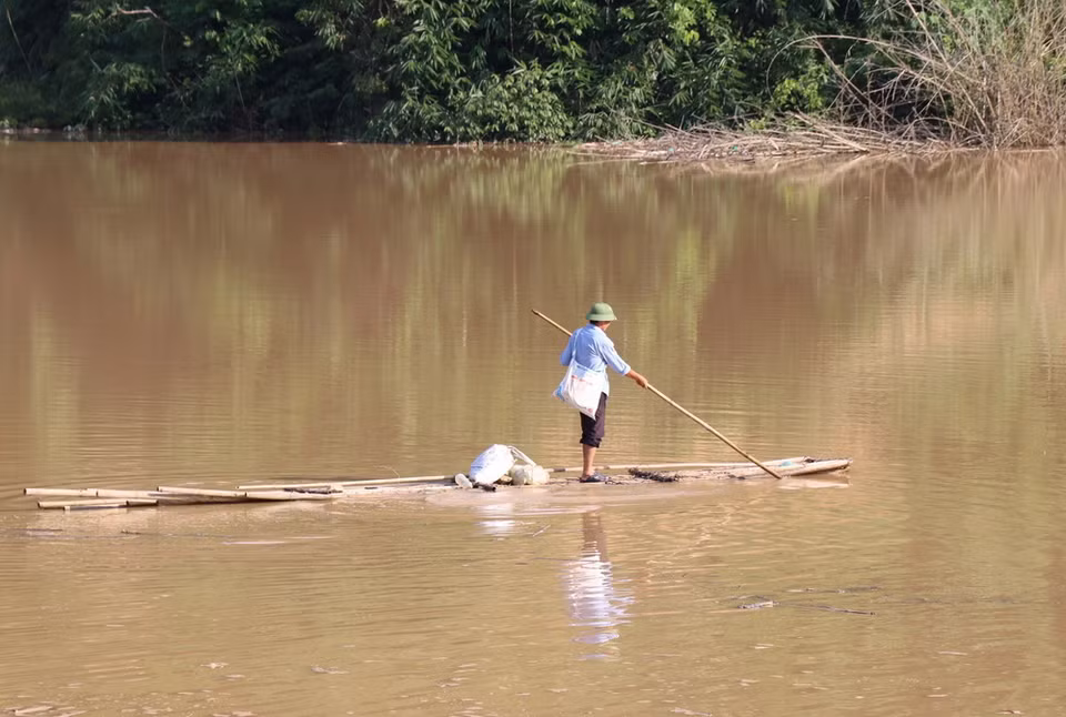 Dù đang cao điểm mùa mưa lũ, người dân vẫn di chuyển bằng bè mảng qua lòng hồ thủy điện trên đường đi nương rẫy. (Ảnh: Xuân Tiến/TTXVN)