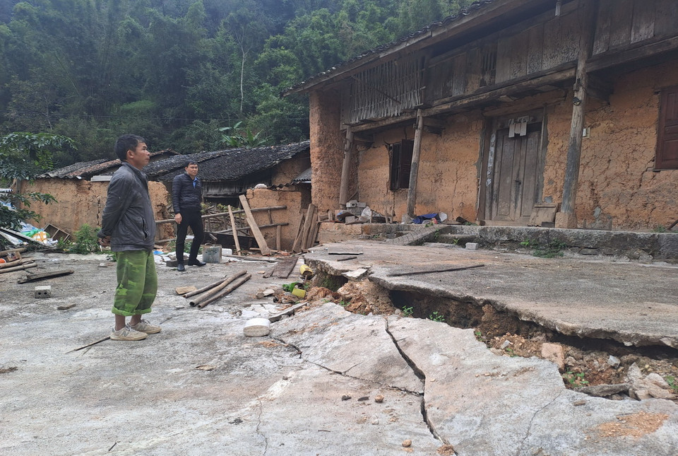 Người dân làng cổ Thiên Hương bên ngôi nhà cổ của mình với những vết nứt 'nuốt chửng.' (Ảnh: Đức Thọ/TTXVN)