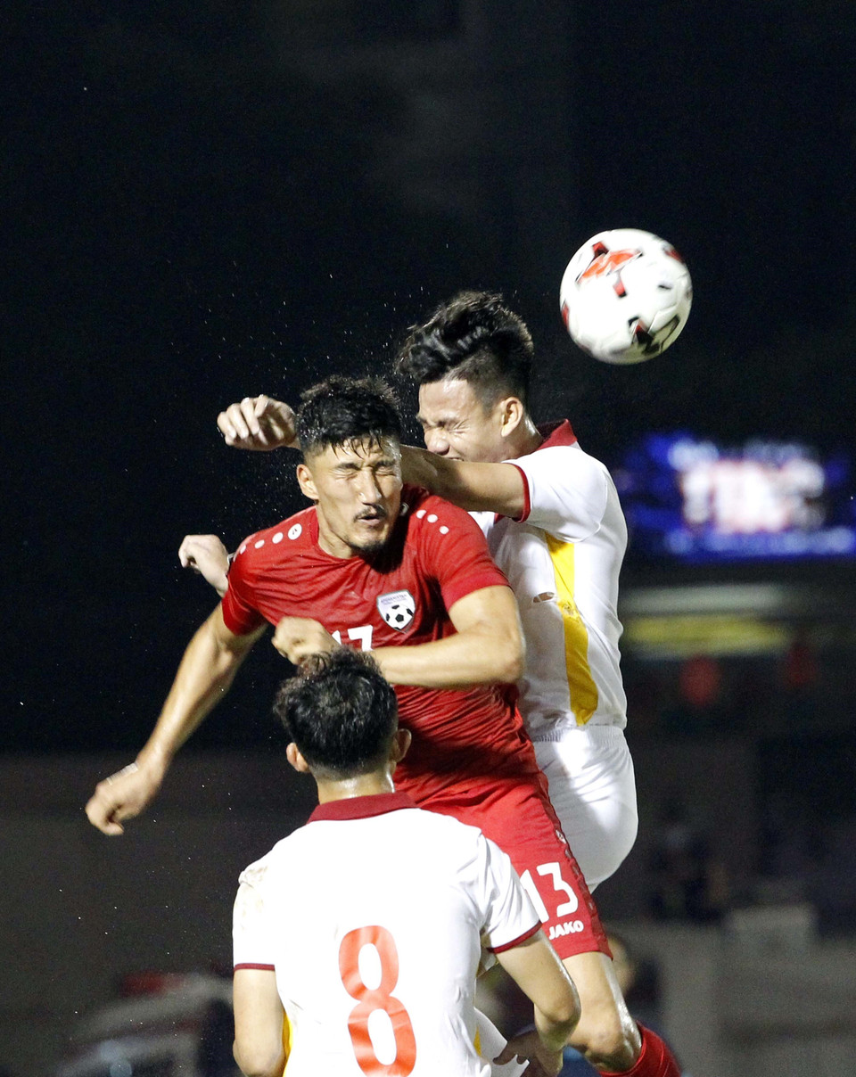 Pha tranh bóng giữa các tuyển thủ Việt Nam (áo trắng) với các cầu thủ Afghanistan (áo đỏ). (Ảnh: Thanh Vũ/TTXVN)