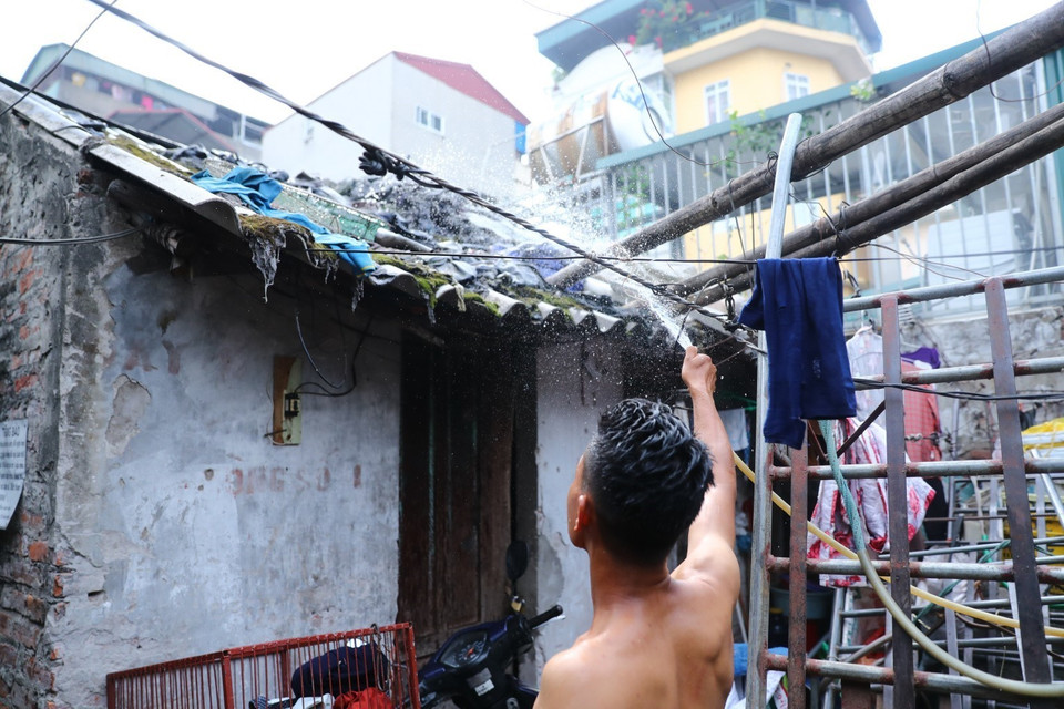 Trước cái nóng như rang, người lao động ở xóm trọ Phúc Xá phải phun nước liên tục lên mái nhà để giảm nhiệt. (Ảnh: Thành Đạt/TTXVN)