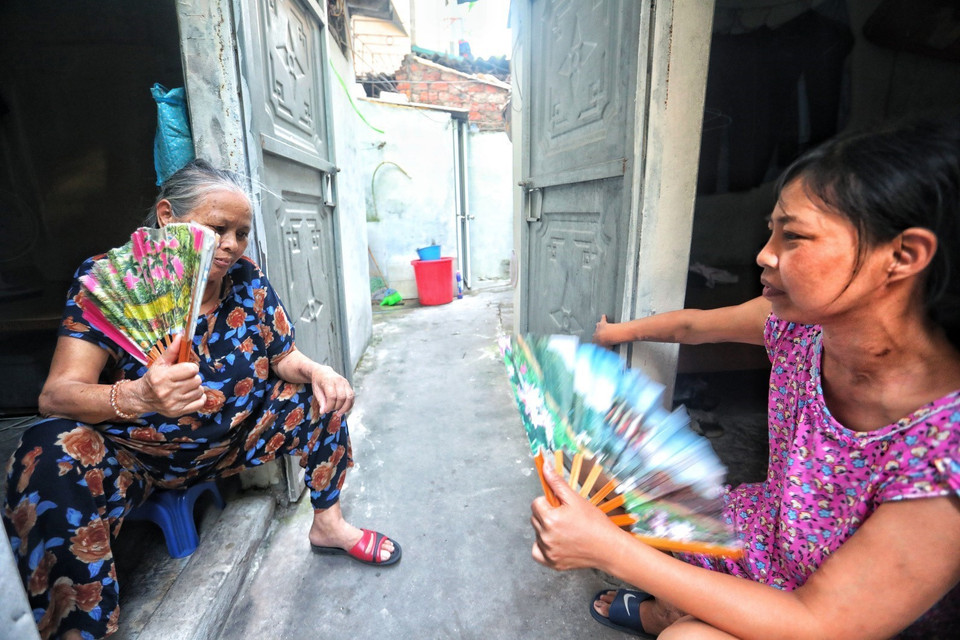  Nhiều bệnh nhân ở xóm chạy thận Lê Thanh Nghị chọn cách ra cửa ngồi quạt tay để chống chọi với cái nóng như thiêu đốt trong những căn phòng trọ chật hẹp. (Ảnh: Thành Đạt/TTXVN)