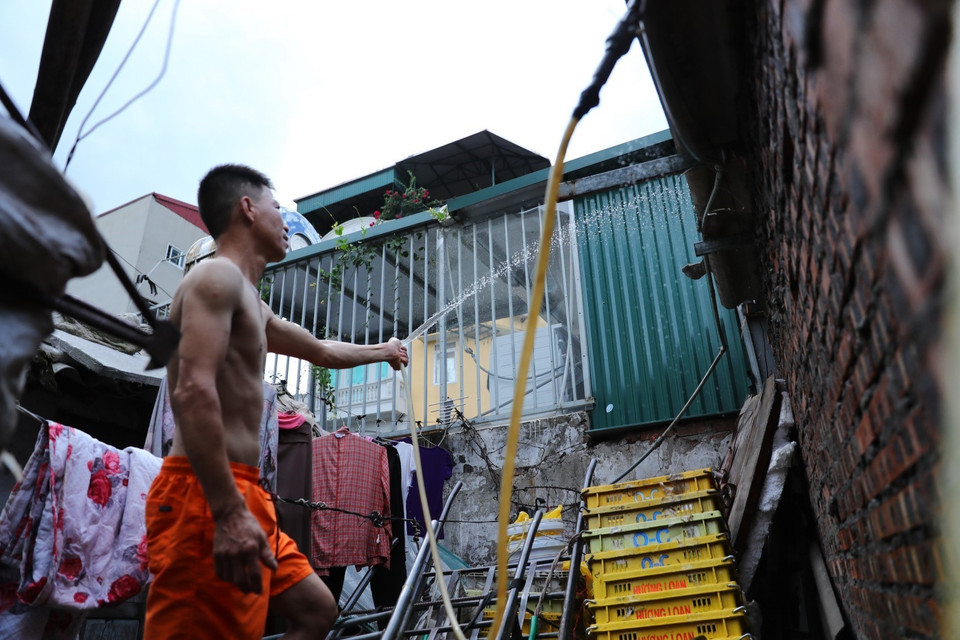 Trước cái nóng như rang, người lao động ở xóm trọ Phúc Xá phải phun nước liên tục lên mái nhà để giảm nhiệt. (Ảnh: Thành Đạt/TTXVN)