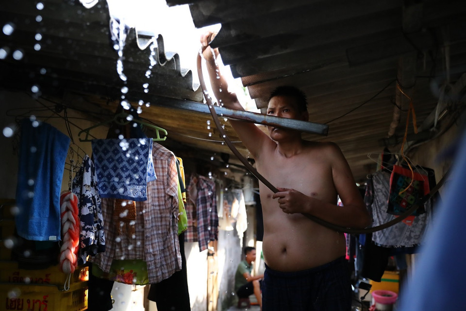 Trước cái nóng như rang, người lao động ở xóm trọ Phúc Xá phải phun nước liên tục lên mái nhà để giảm nhiệt. (Ảnh: Thành Đạt/TTXVN)