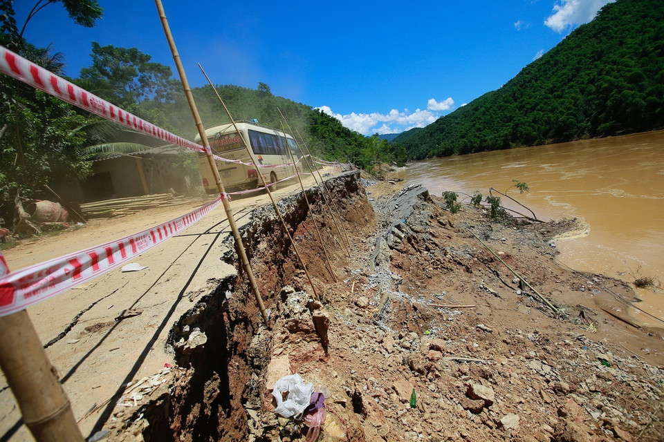 Một chiếc xe khách mạo hiểm di chuyển qua tuyến đường Thủy điện Trung Sơn, bị sạt lở chân đế do nước sông Mã dâng cao gây ra. Đây là con đường nối liền ba xã Thành Sơn-Trung Sơn (huyện Quan Hóa) và xã Mường Lý, huyện Mường Lát. (Ảnh: Quang Quyết/TTXVN)