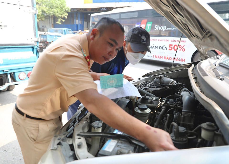 Đại úy công an Đinh Văn Toàn (PC08 Hưng Yên) kiểm tra số khung, số máy của xe đến đăng kiểm tại Trung tâm đăng kiểm xe cơ giới 2906V. (Ảnh: Hoàng Hiếu/TTXVN)