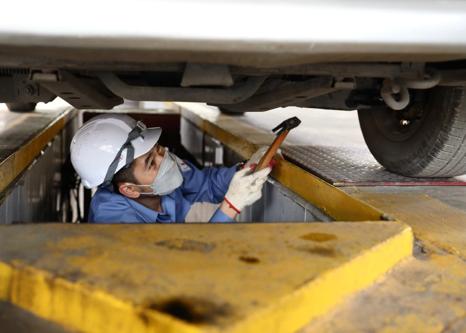 Nhân viên đăng kiểm Trung tâm đăng kiểm xe cơ giới 2906V kiểm tra gầm xe. (Ảnh: Hoàng Hiếu/TTXVN)