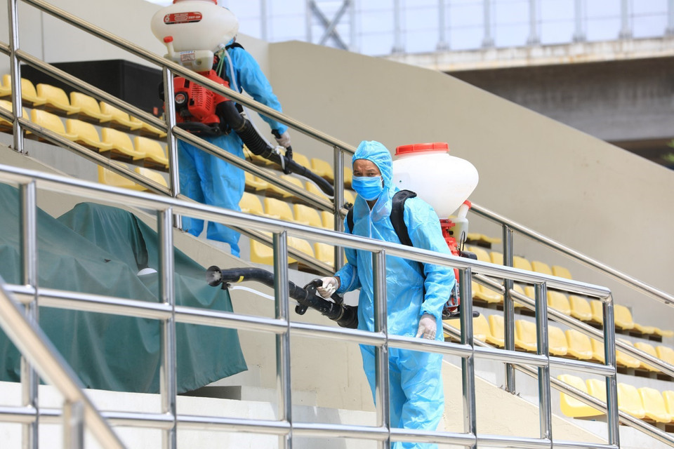 Nhân viên y tế quận Đống Đa phun thuốc khử trùng tại chỗ ngồi trước khi người dân đến lấy mẫu xét nghiệm. (Ảnh: Thành Đạt/TTXVN)