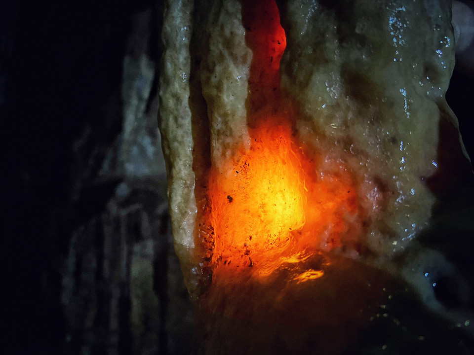 Du khách thử làm thí nghiệm cho ánh sáng xuyên qua nhũ đá. (Ảnh: Mai Mai/Vietnam+)