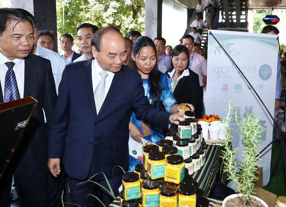 Thủ tướng Nguyễn Xuân Phúc và các đại biểu tham quan các gian hàng trưng bày sản phẩm tại triển lãm. (Ảnh: Thống Nhất/TTXVN)