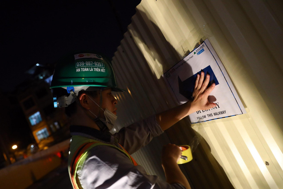 Lực lượng chức năng dán biển báo phân luồng giao thông tại đường Quốc Tử Giám. (Ảnh: Huy Hùng/TTXVN)