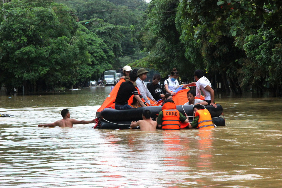 Cán bộ, chiến sỹ Công an Hà Giang hỗ trợ nhân dân qua vùng lũ. (Ảnh: Minh Tâm/Vietnam+)