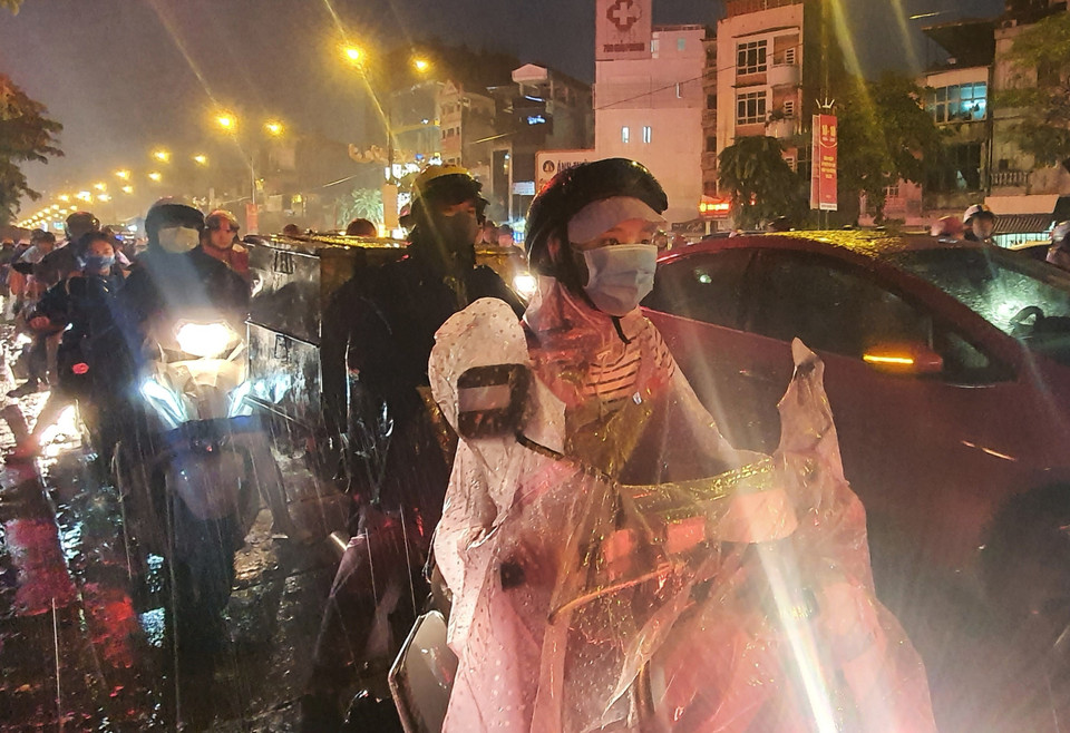Người dân dầm mưa trong khi tham gia giao thông trên đường Giải Phóng. (Ảnh: Danh Lam/TTXVN)