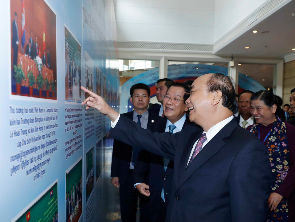  Thủ tướng Nguyễn Xuân Phúc và Thủ tướng Vương quốc Campuchia Samdech Techo Hun Sen xem một số hình ảnh trưng bày tại Hội nghị. (Ảnh: Thống Nhất/TTXVN)