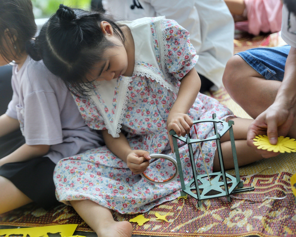 Em nhỏ trải nghiệm làm đèn lồng. (Ảnh: Tuấn Đức/TTXVN)