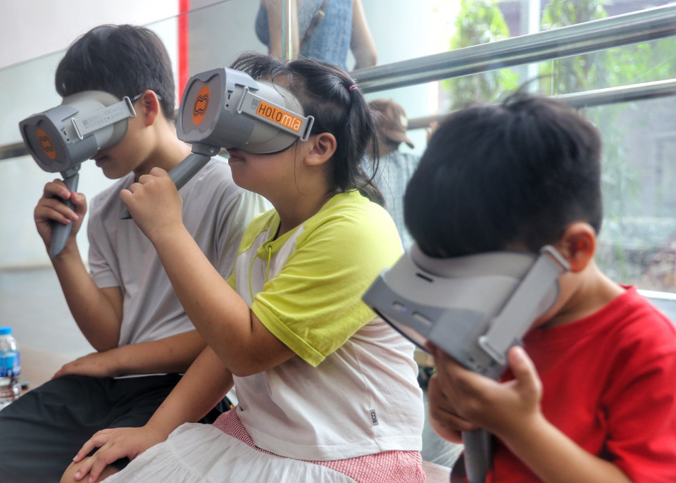 Em nhỏ trải nghiệm công nghệ thực tế ảo. (Ảnh: Tuấn Đức/TTXVN)