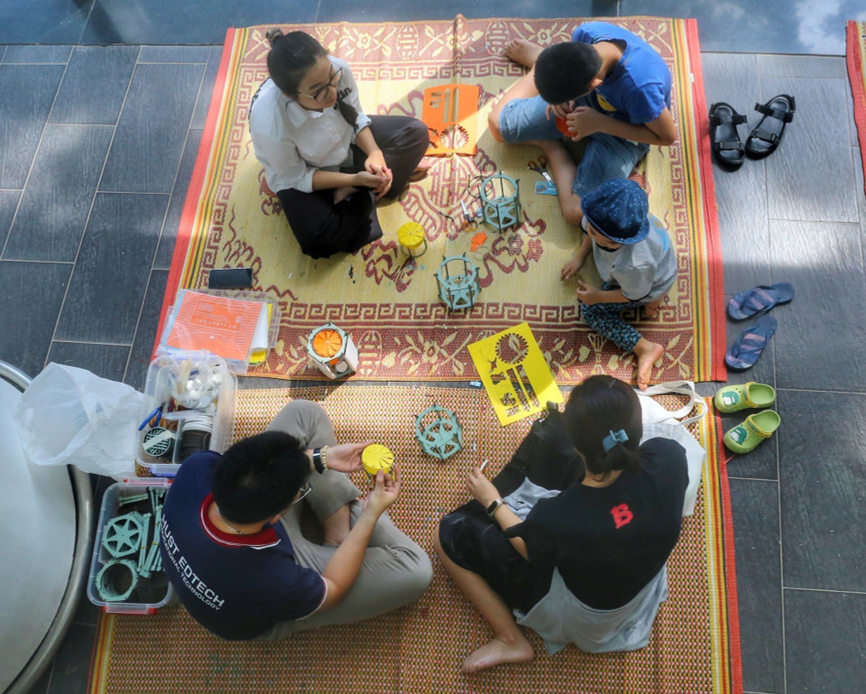 Em nhỏ cùng phụ huynh trải nghiệm làm đèn lồng. (Ảnh: Tuấn Đức/TTXVN)