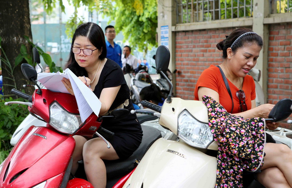 Phụ huynh các thí sinh chờ ngoài điểm Trường Trung học phổ thông Lương Thế Vinh, Hà Nội. (Ảnh: Thành Đạt/TTXVN)