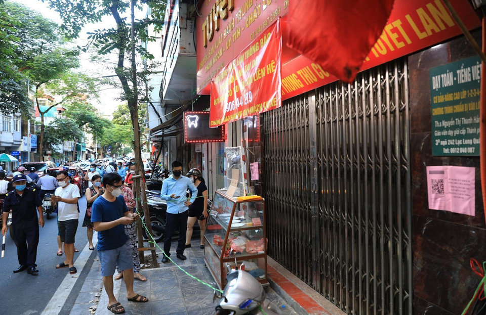 Mặc dù các cửa hàng đã đóng cửa nhưng người dân vẫn xếp hàng chờ lấy bánh Trung Thu. (Ảnh: Thành Đạt/TTXVN)