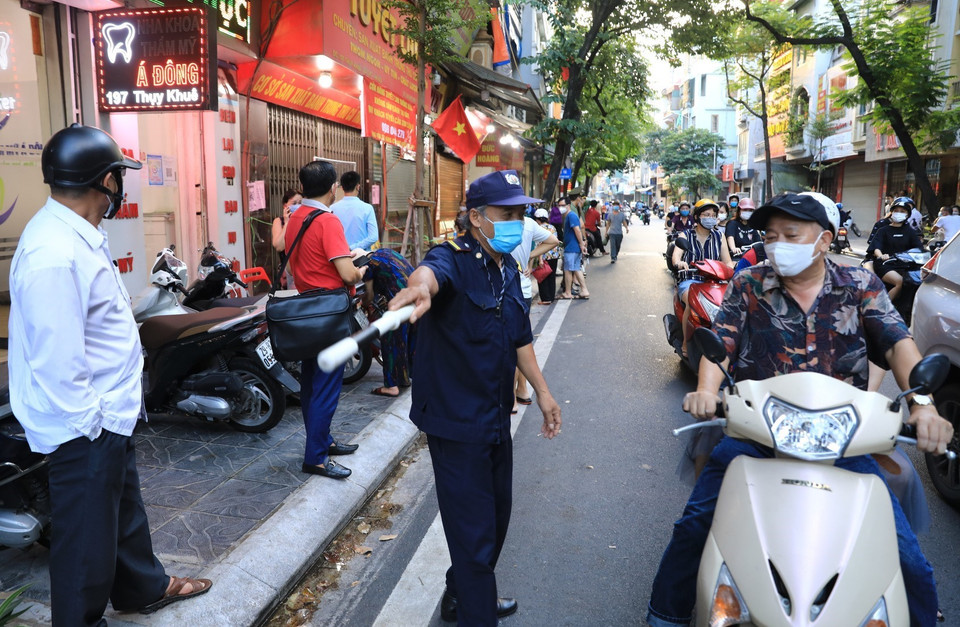 Lực lượng chức năng phường Thụy Khuê liên tục nhắc nhở người dân chờ mua bánh Trung Thu di chuyển tránh tình trạng tắc nghẽn giao thông. (Ảnh: Thành Đạt/TTXVN)