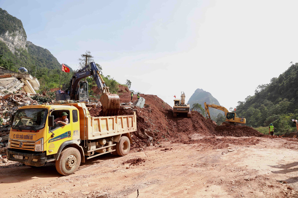 Ngành giao thông tỉnh Quảng Bình huy động phương tiện máy móc và nhân lực để mở đường tạm trên đoạn Quốc lộ 12A bị sạt lở nặng thuộc xã Dân Hóa, huyện Minh Hóa. (Ảnh: Vũ Sinh/TTXVN)