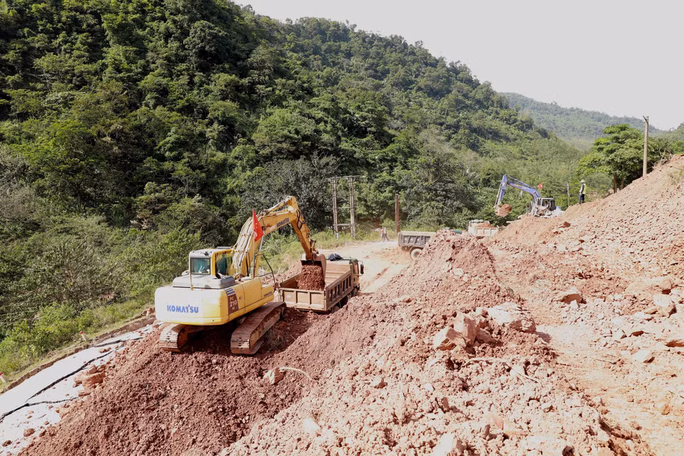 Ngành giao thông tỉnh Quảng Bình huy động phương tiện máy móc và nhân lực để mở đường tạm trên đoạn Quốc lộ 12A bị sạt lở nặng thuộc xã Dân Hóa, huyện Minh Hóa. (Ảnh: Vũ Sinh/TTXVN)