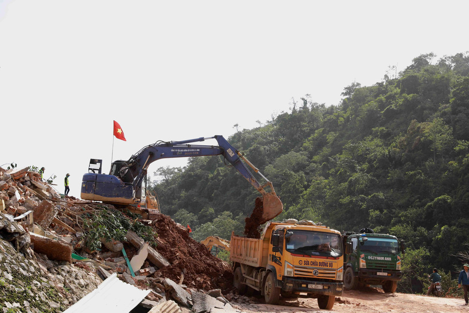 Ngành giao thông tỉnh Quảng Bình huy động phương tiện máy móc và nhân lực để mở đường tạm trên đoạn Quốc lộ 12A bị sạt lở nặng thuộc xã Dân Hóa, huyện Minh Hóa. (Ảnh: Vũ Sinh/TTXVN)