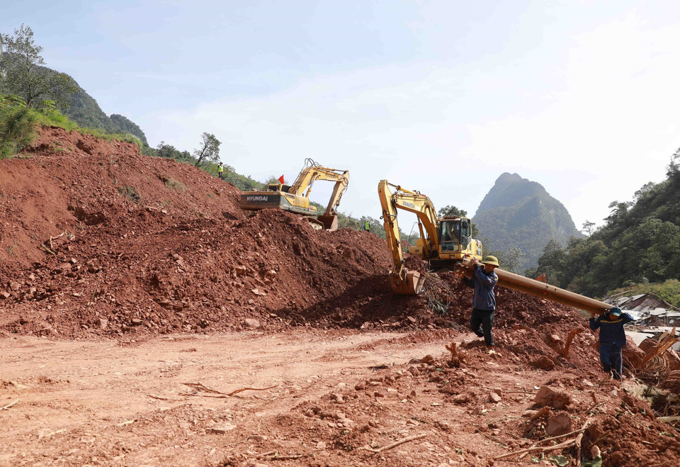 Ngành giao thông tỉnh Quảng Bình huy động phương tiện máy móc và nhân lực để mở đường tạm trên đoạn Quốc lộ 12A bị sạt lở nặng thuộc xã Dân Hóa, huyện Minh Hóa. (Ảnh: Vũ Sinh/TTXVN)