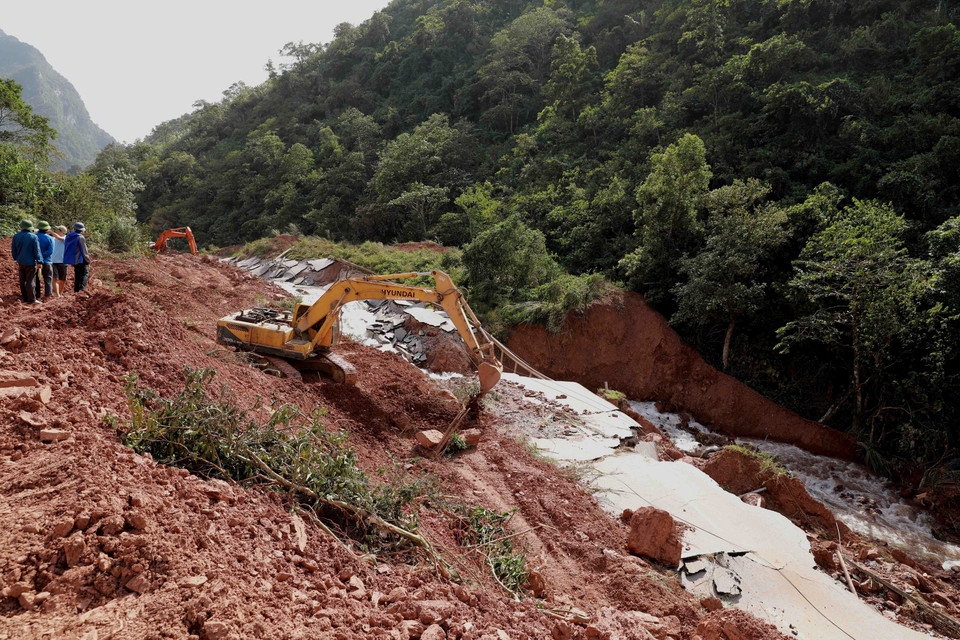 Ngành giao thông tỉnh Quảng Bình huy động phương tiện máy móc và nhân lực để mở đường tạm trên đoạn Quốc lộ 12A bị sạt lở nặng thuộc xã Dân Hóa, huyện Minh Hóa. (Ảnh: Vũ Sinh/TTXVN)