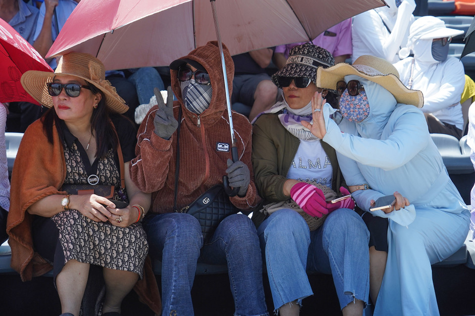Chị em hồ hởi trên khán đài với đầy đủ 'combo' chống nắng gồm mũ rộng vành, kính râm, găng tay và áo khoác chống nắng. (Ảnh: Việt Anh/Vietnam+)
