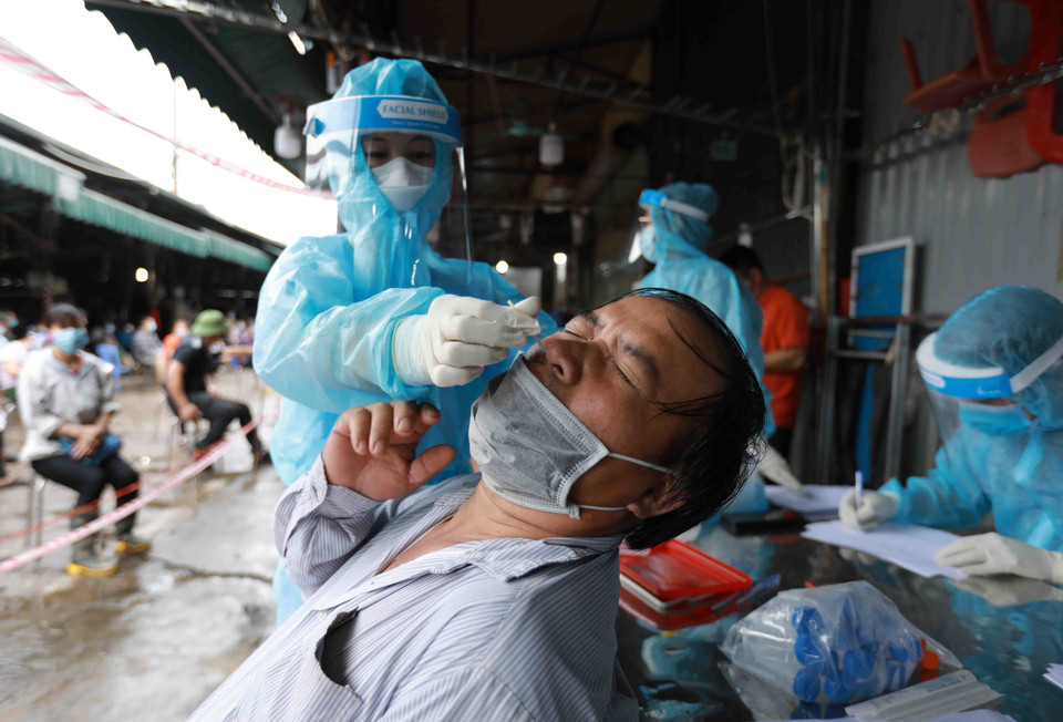  Nhân viên Y tế của Trung tâm kiểm soát bệnh tật Hà Nội lấy mẫu xét nghiệm cho các tiểu thương tại chợ Phùng Khoang.(Ảnh: Vũ Sinh/TTXVN)