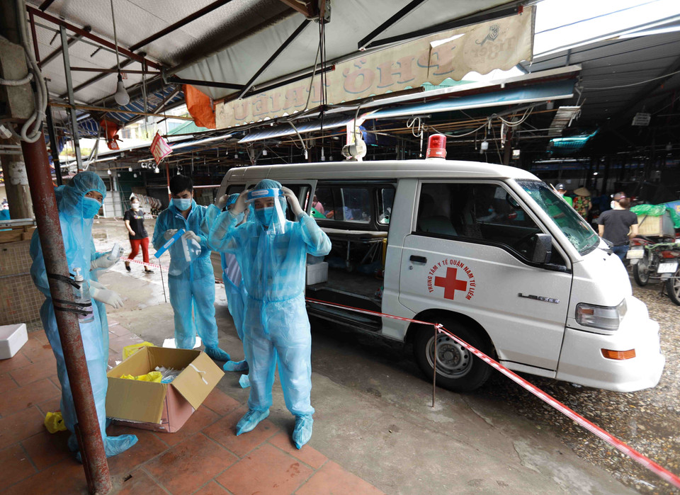 Nhân viên y tế của Trung tâm Kiểm soát bệnh tật Hà Nội chuẩn bị lấy mẫu xét nghiệm cho các tiểu thương tại chợ Phùng Khoang. (Ảnh: Vũ Sinh/TTXVN)