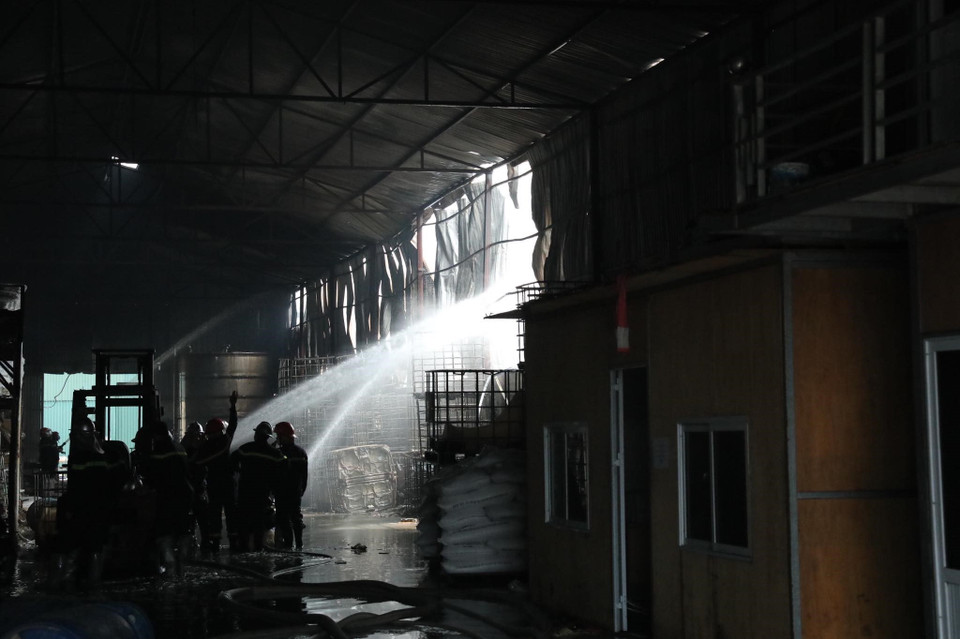 Lực lượng chức năng tiến vào bên trong kho hàng để chữa cháy. (Ảnh: Nhật Anh/TTXVN)