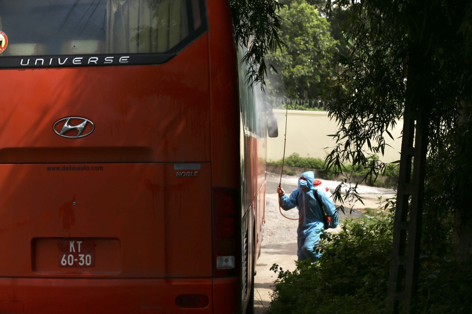 Phun khử khuẩn xe đưa hành khách về khu cách ly tập trung Trường quân sự Bộ Tư lệnh Thủ đô. (Ảnh: Minh Quyết/TTXVN)