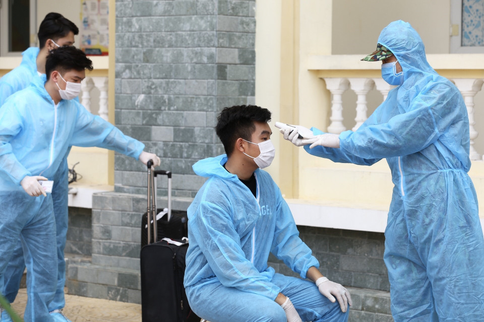 Đo kiểm tra thân nhiệt và làm thủ tục tiếp nhận hành khách về từ Đà Nẵng, tại khu cách ly tập trung Trường quân sự Bộ Tư lệnh Thủ đô. (Ảnh: Minh Quyết/TTXVN)