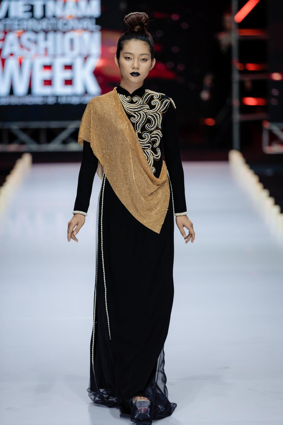 Ngoài việc lựa chọn màu sắc là tông đen với điểm nhấn là màu vàng của loài hoa quý hiếm lan hoàng thảo, nhà thiết kế Minh Châu đã ưu tiên giữ phom dáng truyền thống của chiếc áo dài, tập trung vào kỹ thuật kết cườm đính đá thủ công và phối chất liệu. (Ảnh: CTV)