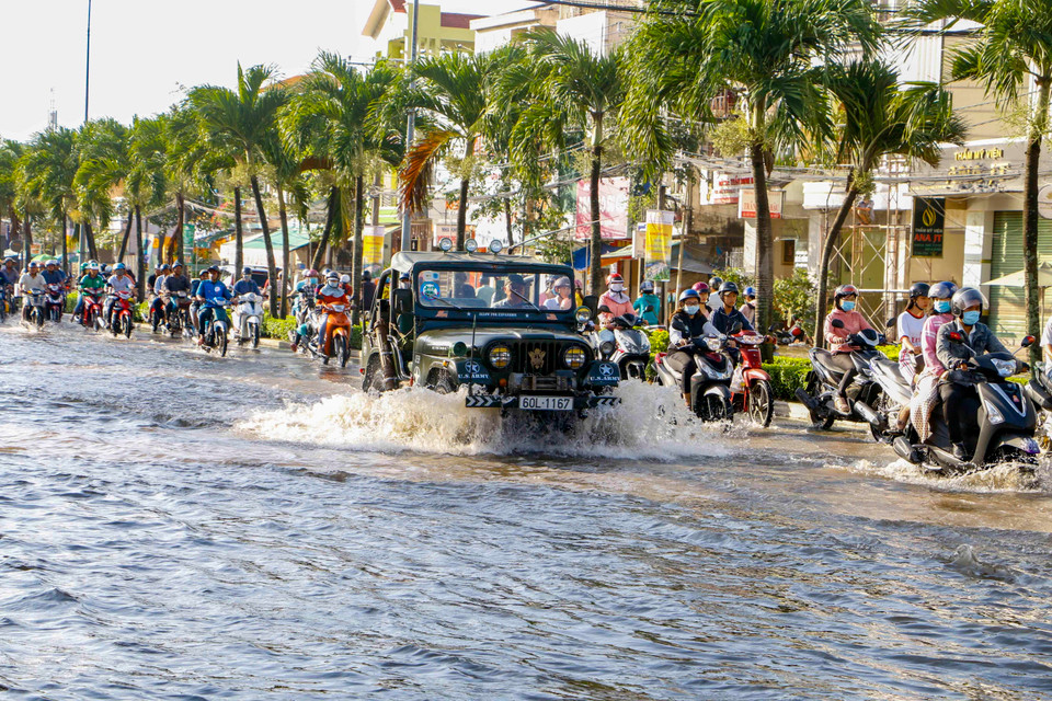 Trên các tuyến đường ngập sâu, người dân phải di chuyển vào sát dải phân cách để tránh xe bị chết máy. (Ảnh: Thanh Liêm/TTXVN)