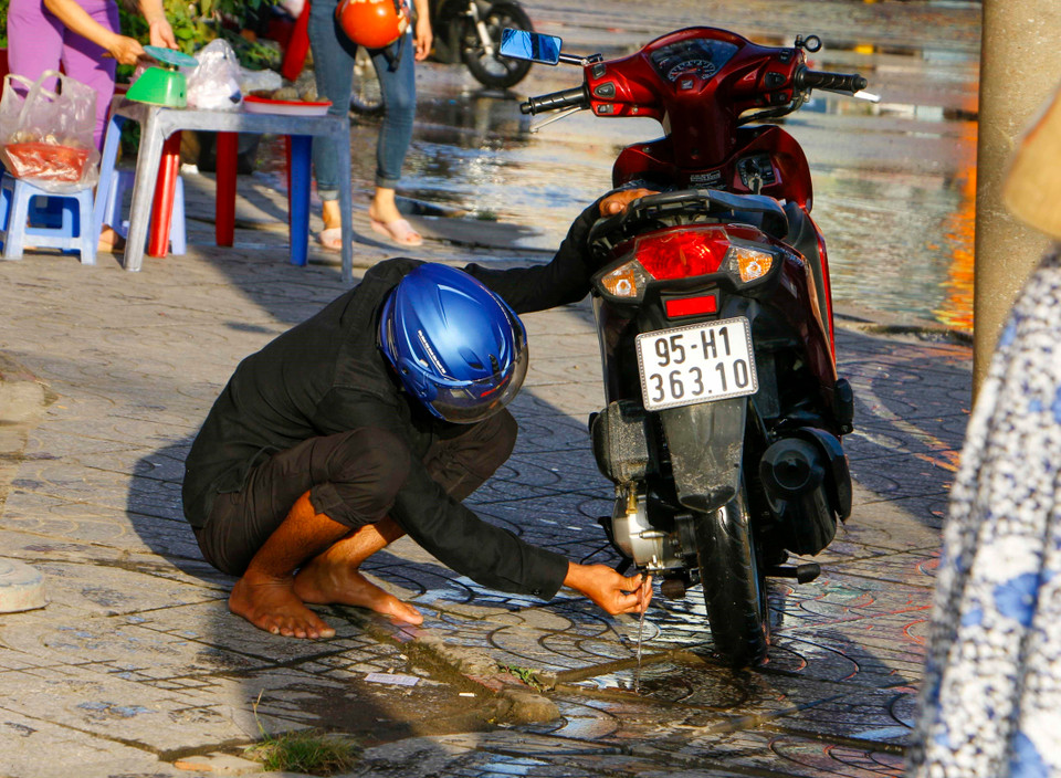 Một người đi xe máy vượt qua khu vực ngập sâu bị chết máy. (Ảnh: Thanh Liêm/TTXVN)