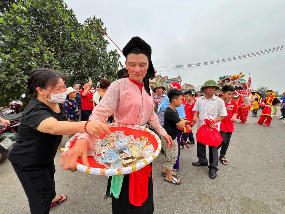 Những nhân vật giả trang tham gia đoàn rước nhằm mua vui hội làng nhận quà từ người dân đứng ven đường. (Ảnh: Mai Mai/Vietnam+)