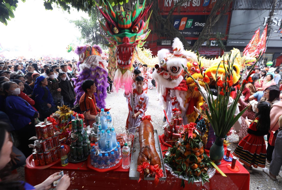 Đội lân sư rồng thuộc đoàn rước ghé vào mâm lễ của các gia đình hai bên đường để cầu chúc một năm làm ăn đắc lộc. (Ảnh: Anh Tuấn/TTXVN)