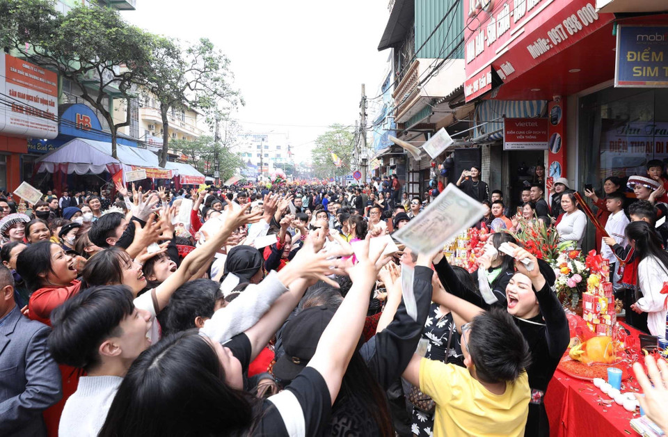 Người dân và du khách hứng lộc trước đám rước từ đền Tả Phủ về đền Kỳ Cùng. (Ảnh: Anh Tuấn/TTXVN)